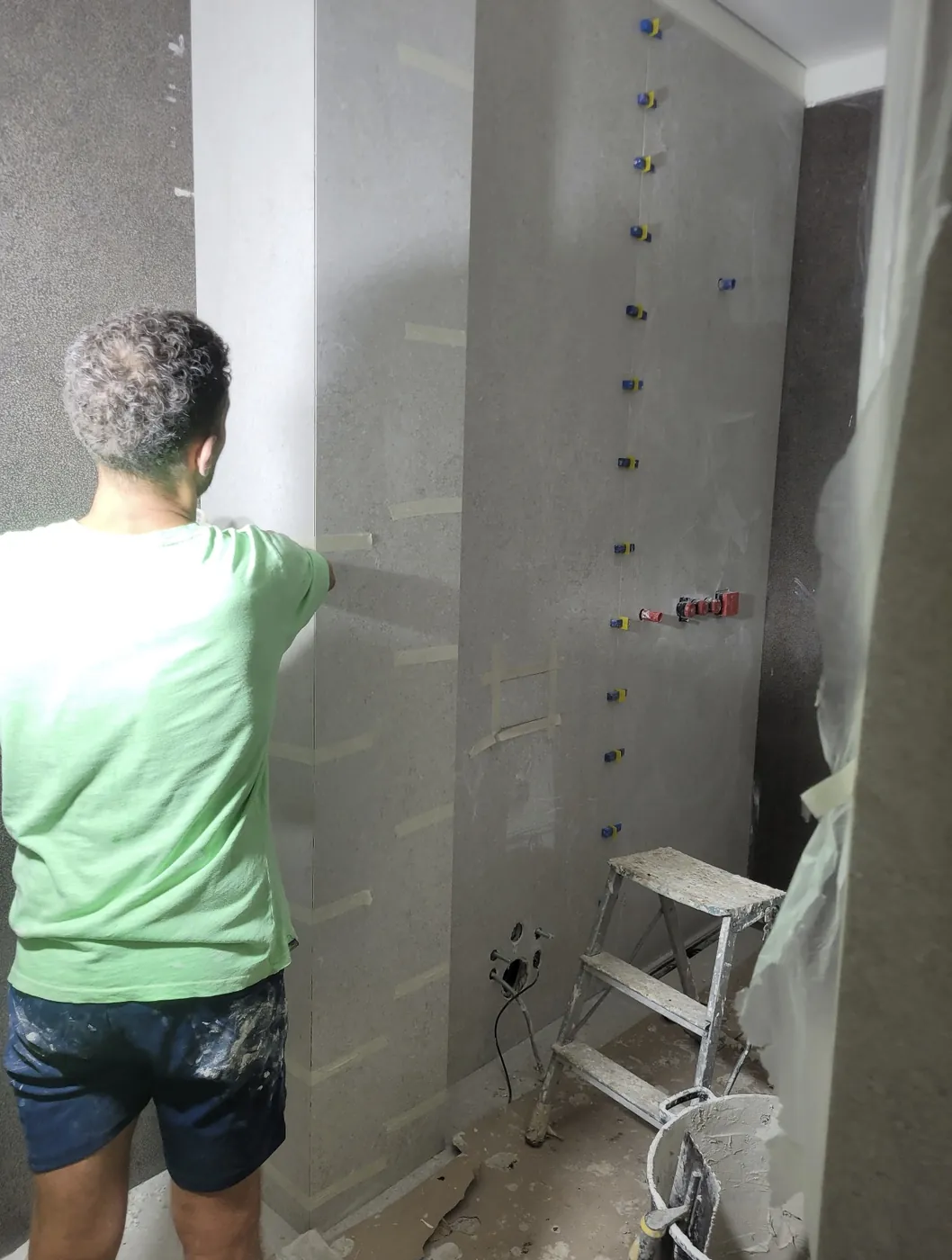 Posa delle grandi lastre in gres da 120 × 280 cm con i livellatori, nel bagno di una villa a Roma Olgiata