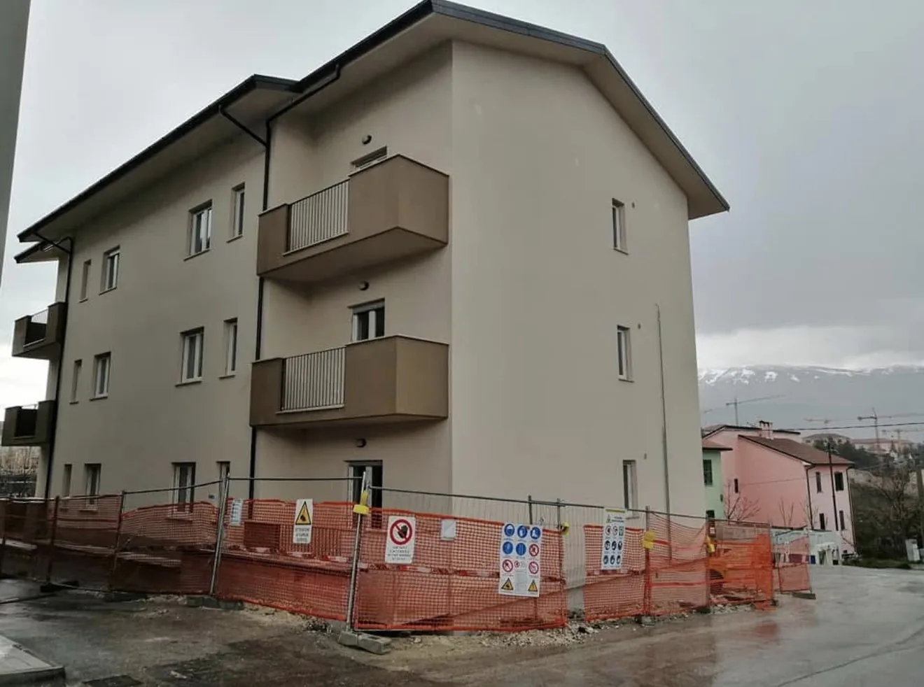 Lato della palazzina a L’Aquila con finestre e porte-finestre in PVC bianco, cantiere con il Superbonus