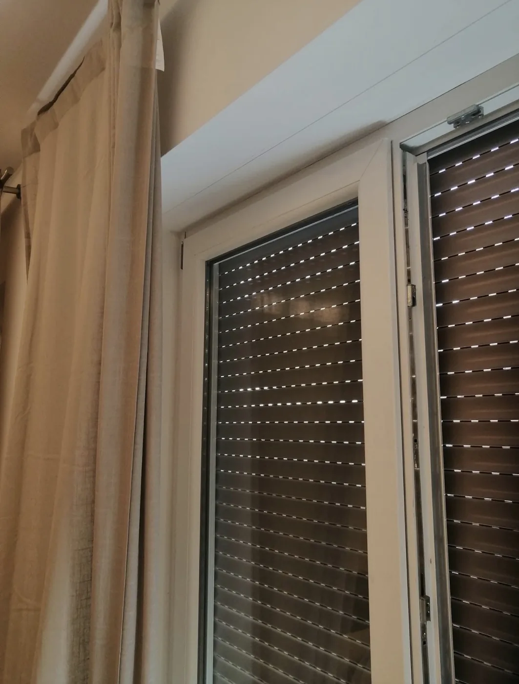 Dettaglio del telaio di un infisso in PVC bianco con tapparella avvolgibile, cantiere a Roma Monte Sacro