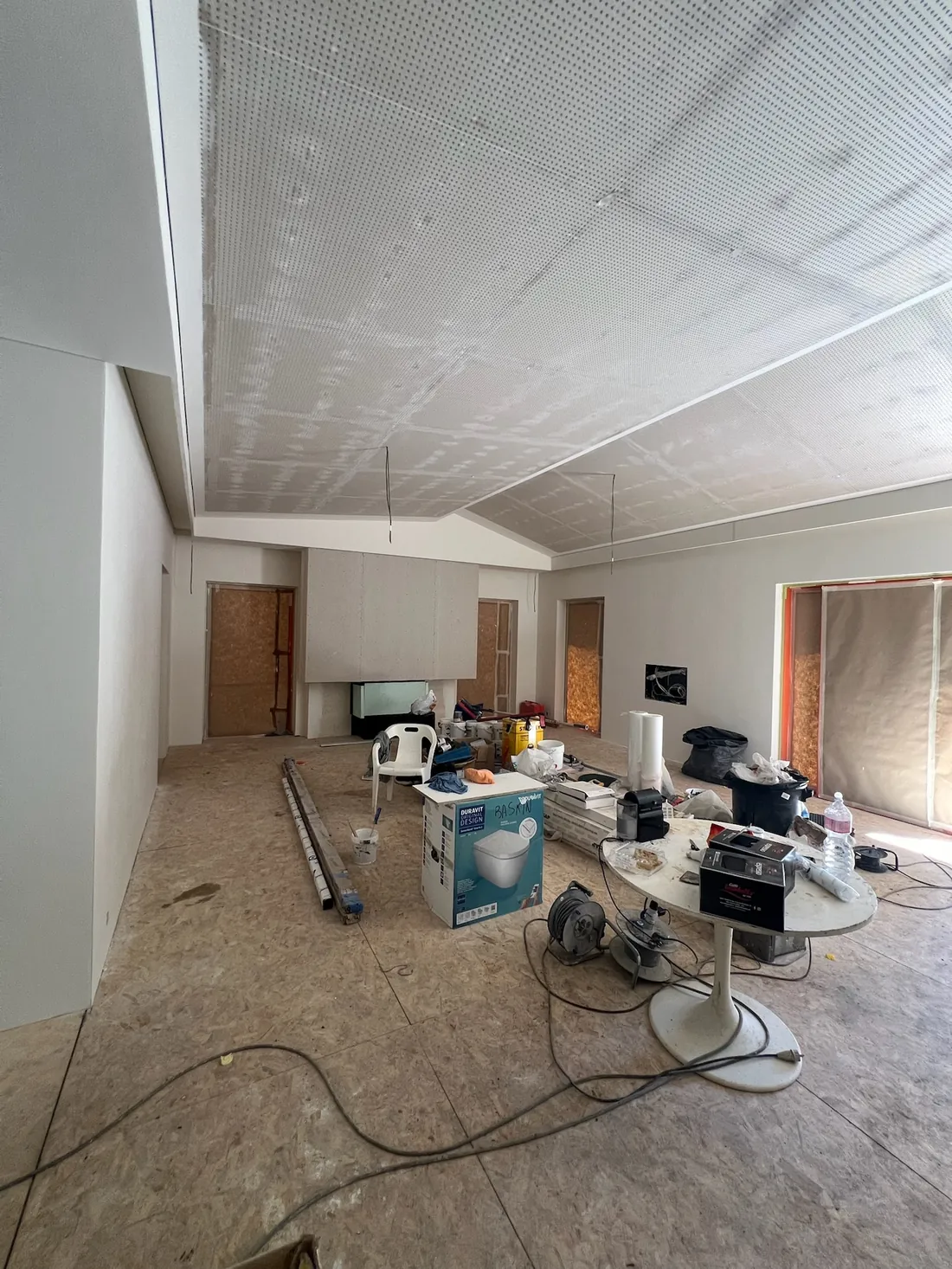 Soggiorno durante i lavori: controsoffitto in cartongesso forato, pavimento in OSB, materiali in cantiere